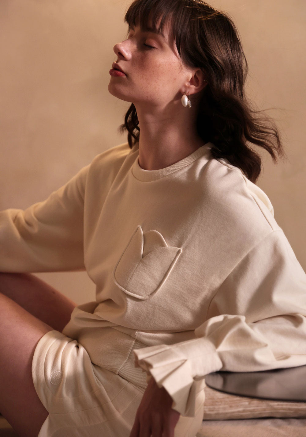 Virginie Voncken marque de luxe durable made in France. Sweatshirt avec poche Tulipe et manches ballons aux poignets soulignés de plis corolle inspiré des fleurs. Réalisé en coton biologiques sans teinture. Ce sweatshirt femme made in France est issu de la ligne CRU, premier vestiaire entièrement réalisé sans aucun blanchiment ni teinture. Marque de mode durable fabriquée en France, Virginie Voncken propose sa vision Conscious Luxury à travers des collections au minimalisme romantique.