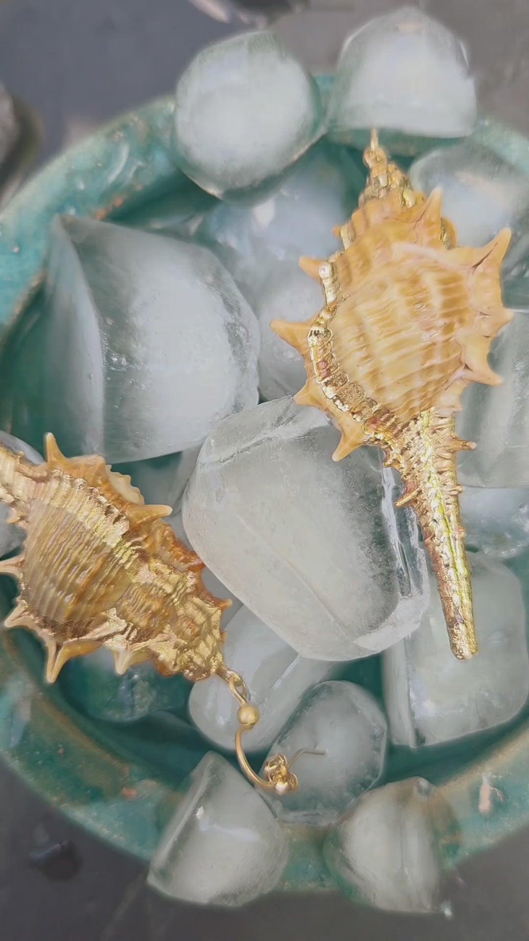 Vidéo d'une paire de boucle d'oreille, bijoux made in France, en coquillage et or Gold Field.Un joli coquillage avec des piques, dorés à l'or fin sur un lit de glaçons comme un plateau de fruit de mer. très chic et très légères c'est boucle d'oreilles sont parfaites pour l'été.