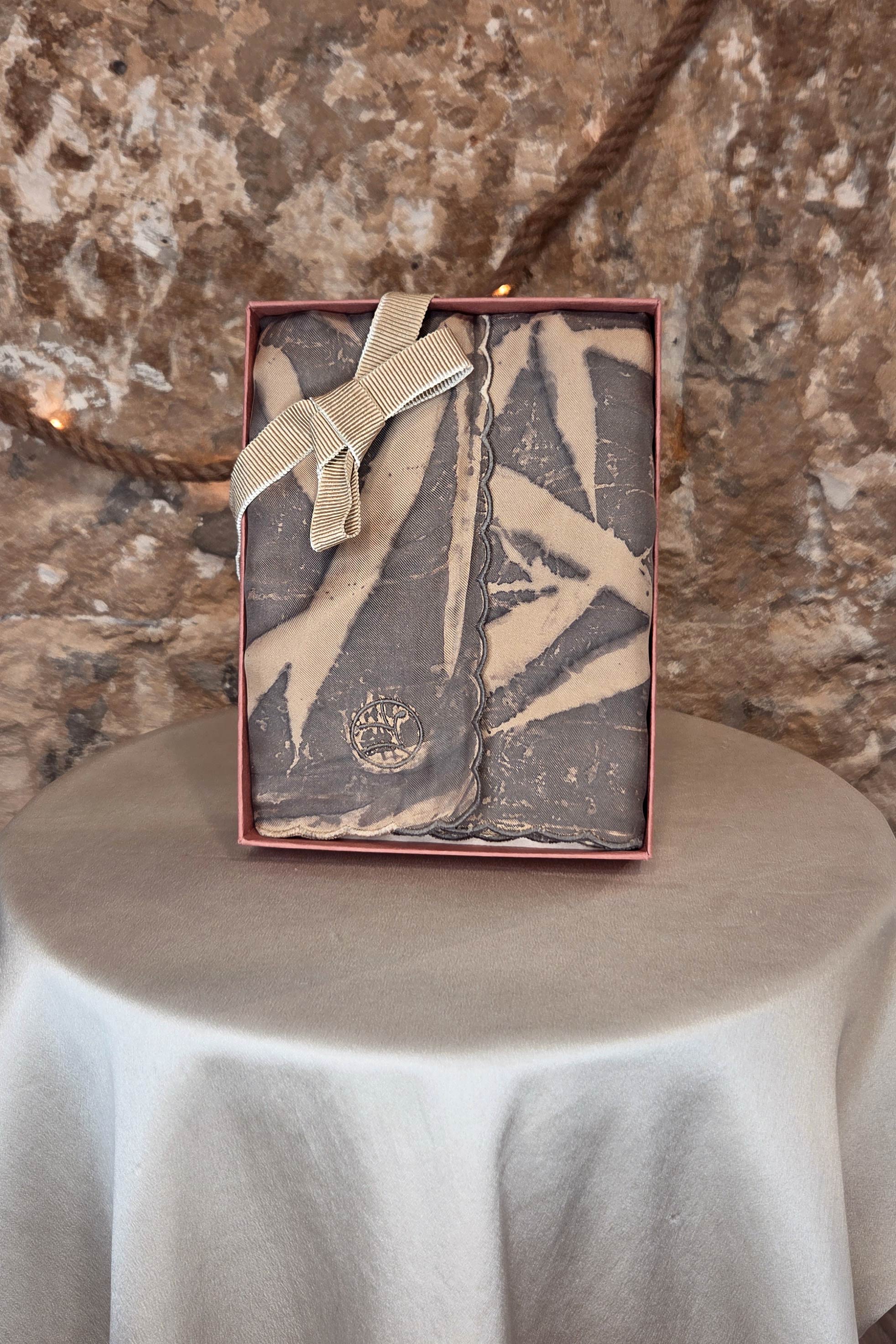 Chaque foulard en soie teinture naturelle de Virginie Voncken est glissé dans un écrin coloris Terracotta et fermé par un ruban en gros grain teinture naturelle.